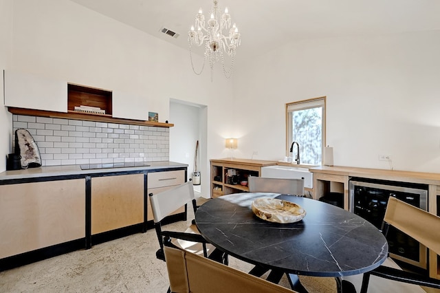 dining space featuring light colored carpet, high vaulted ceiling, a notable chandelier, and sink