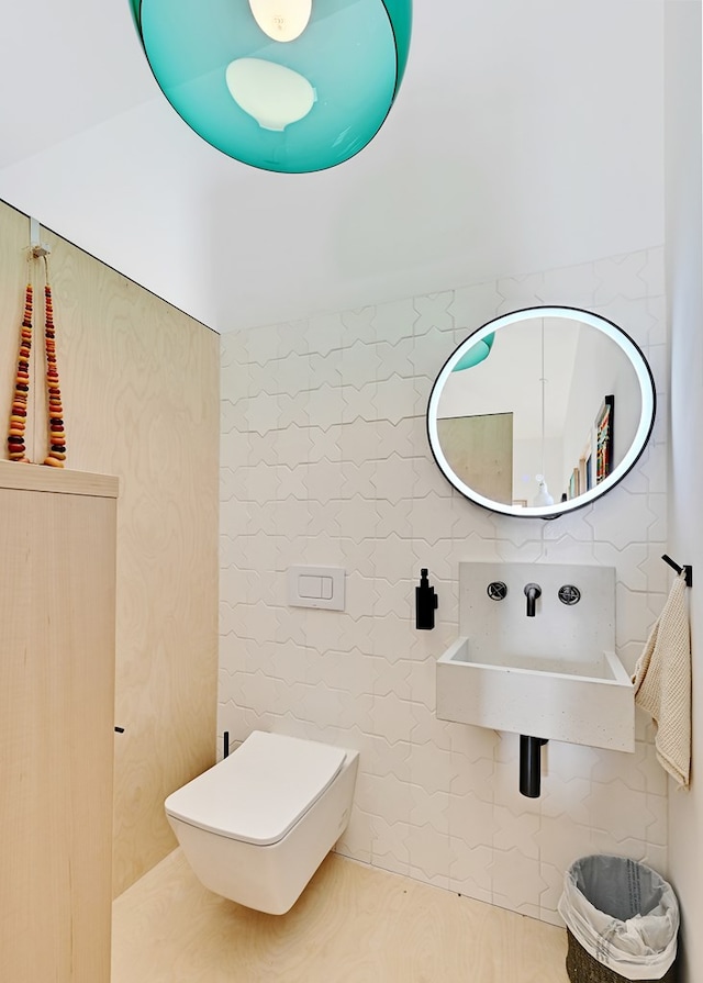 bathroom with sink, tile walls, and toilet