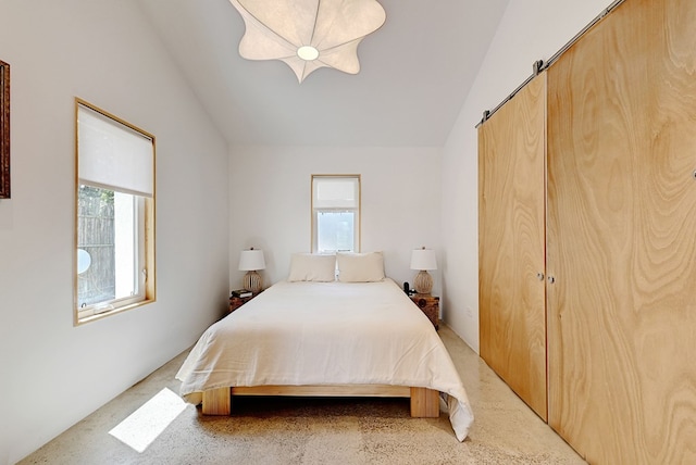 bedroom featuring a barn door, light colored carpet, a closet, and vaulted ceiling