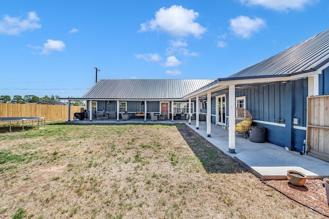 back of property featuring a yard, a patio, and a trampoline