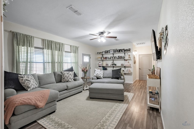 living room featuring hardwood / wood-style floors, ceiling fan, and a textured ceiling