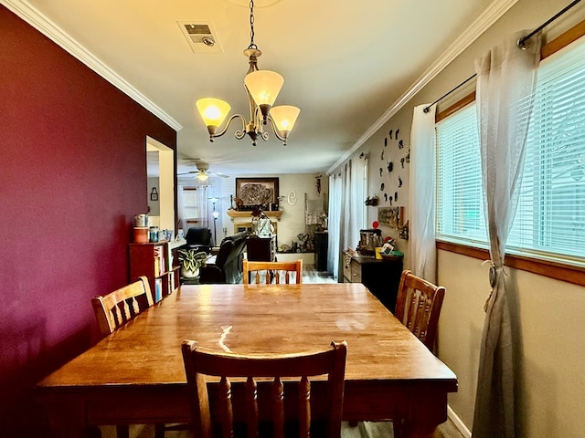 dining space featuring visible vents, ceiling fan with notable chandelier, and ornamental molding