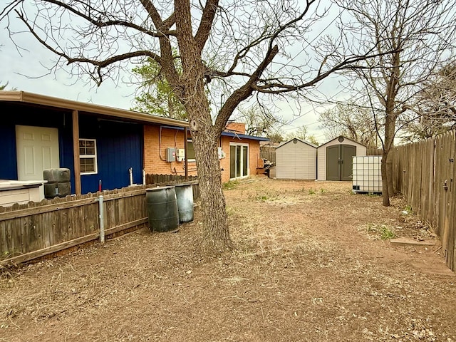 view of yard with an outbuilding, a storage unit, and fence