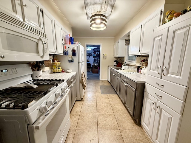 kitchen featuring crown molding, light countertops, light tile patterned flooring, white appliances, and white cabinetry