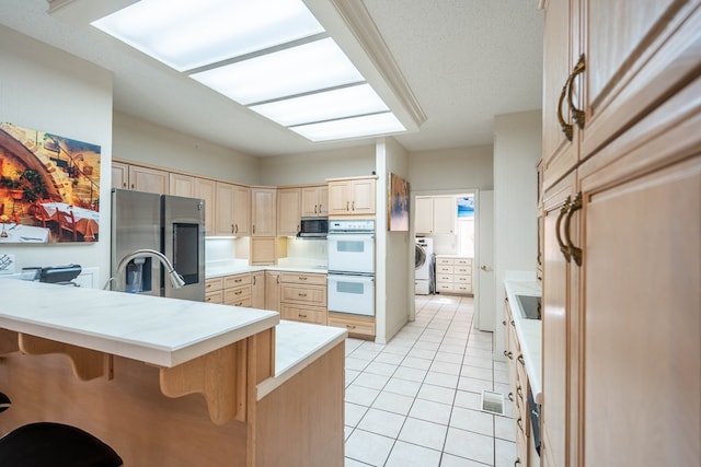 kitchen with washer / dryer, a kitchen breakfast bar, kitchen peninsula, stainless steel appliances, and light brown cabinets