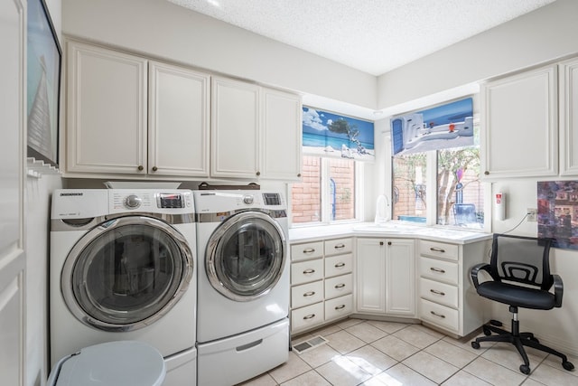 washroom featuring washing machine and clothes dryer, sink, cabinets, a textured ceiling, and light tile patterned floors