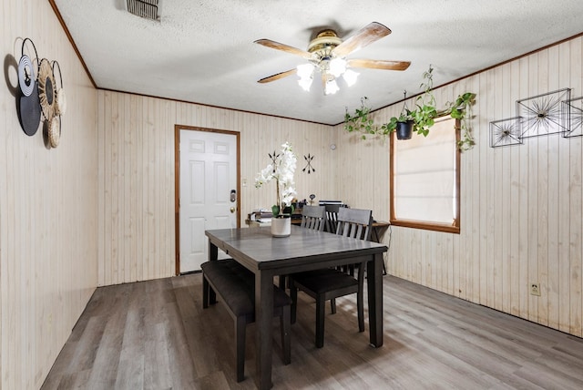 dining room with visible vents, ceiling fan, ornamental molding, wood finished floors, and a textured ceiling