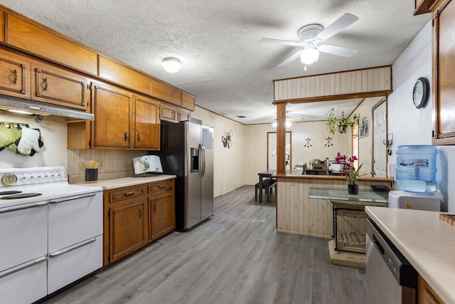 kitchen featuring light countertops, appliances with stainless steel finishes, under cabinet range hood, and brown cabinets