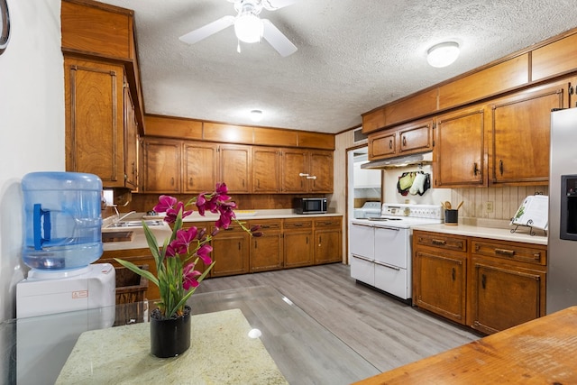 kitchen featuring light countertops, brown cabinetry, light wood-style floors, a textured ceiling, and double oven range