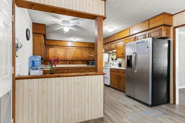 kitchen with white electric range oven, brown cabinets, and stainless steel fridge with ice dispenser