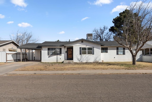 ranch-style home with concrete driveway, an attached carport, fence, and stucco siding