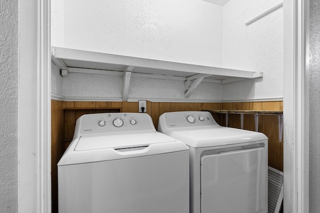 washroom with laundry area, wainscoting, a textured wall, washer and dryer, and wood walls