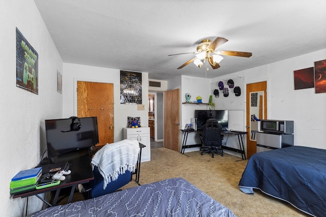 carpeted bedroom with a ceiling fan, visible vents, a textured wall, and a textured ceiling