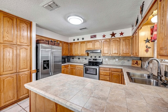 kitchen with sink, appliances with stainless steel finishes, decorative backsplash, tile countertops, and kitchen peninsula