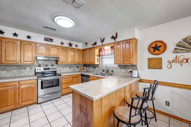 kitchen with sink, light tile patterned floors, appliances with stainless steel finishes, backsplash, and kitchen peninsula