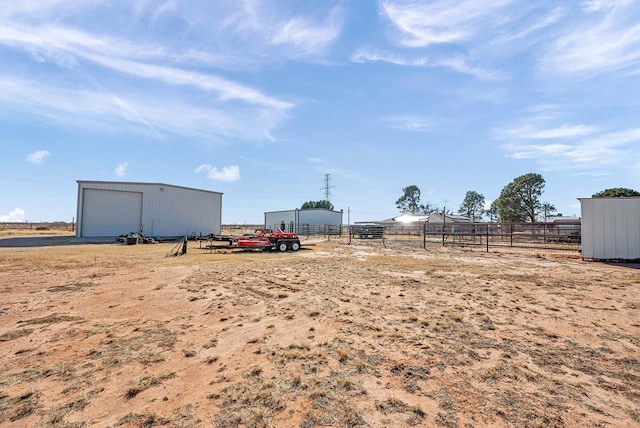 view of yard with a garage, an outbuilding, and a rural view