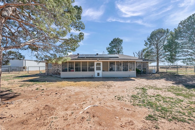 back of property featuring a sunroom and solar panels