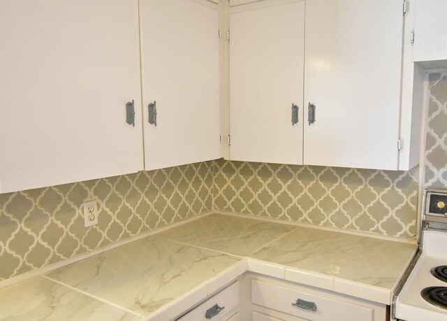 kitchen featuring white cabinets, decorative backsplash, and white range oven