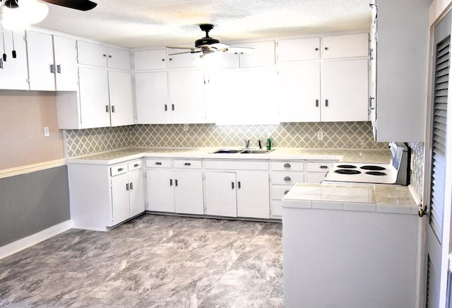 kitchen with tile counters, sink, electric stove, decorative backsplash, and white cabinets