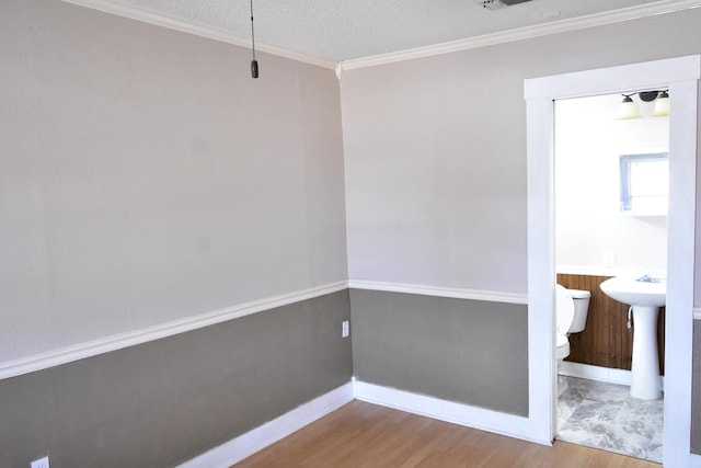 unfurnished room with hardwood / wood-style floors, ornamental molding, sink, and a textured ceiling