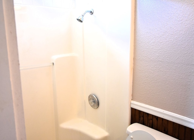 bathroom featuring walk in shower, wood walls, and toilet