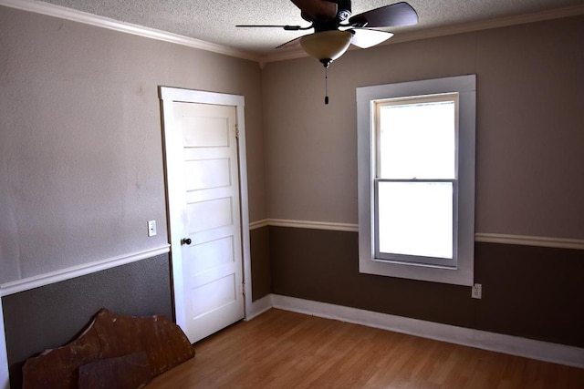 unfurnished room featuring a textured ceiling, light hardwood / wood-style floors, ceiling fan, and crown molding