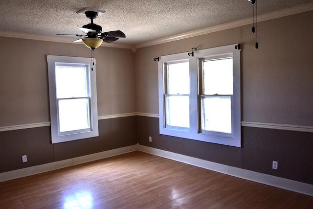 empty room featuring hardwood / wood-style floors, ceiling fan, ornamental molding, and a textured ceiling