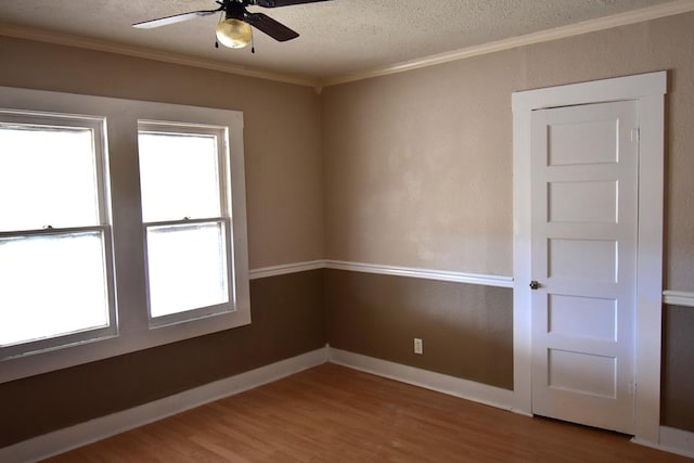 empty room with crown molding, ceiling fan, wood-type flooring, and a textured ceiling