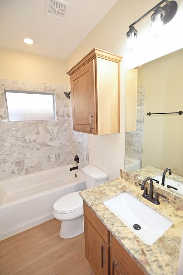 full bathroom featuring hardwood / wood-style floors, vanity, toilet, and tiled shower / bath