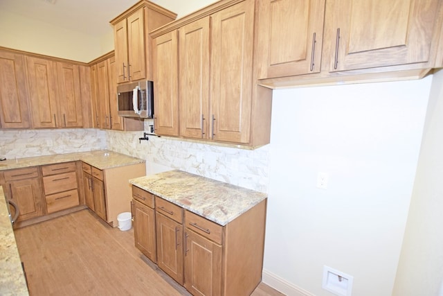 kitchen featuring light hardwood / wood-style floors, light stone countertops, and backsplash