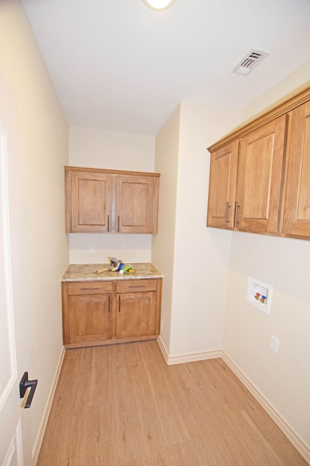 laundry area with light hardwood / wood-style flooring, cabinets, and washer hookup