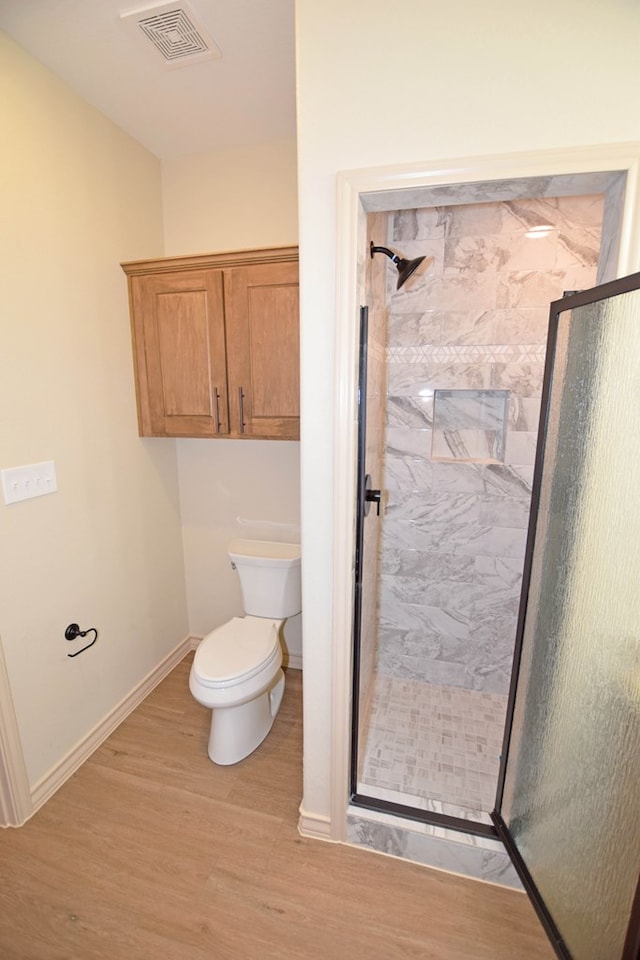 bathroom with toilet, hardwood / wood-style floors, and walk in shower