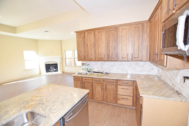 kitchen featuring backsplash, light stone counters, stainless steel appliances, and light hardwood / wood-style flooring