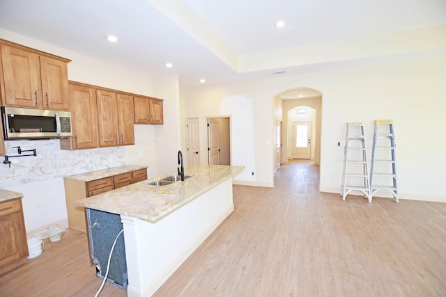 kitchen with light hardwood / wood-style floors, sink, and an island with sink