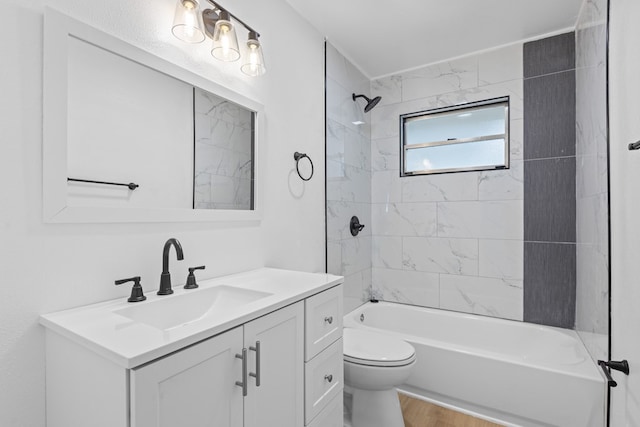 full bathroom with tiled shower / bath combo, vanity, hardwood / wood-style floors, and toilet