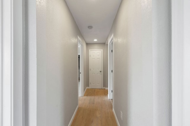 corridor with light wood-style flooring and baseboards