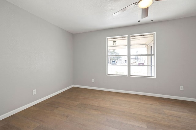 empty room featuring ceiling fan, a textured ceiling, baseboards, and wood finished floors