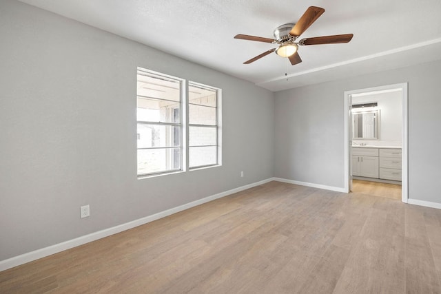 unfurnished bedroom featuring light wood-style floors, a ceiling fan, baseboards, and connected bathroom