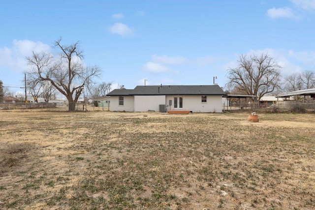 rear view of house with a lawn, cooling unit, and fence