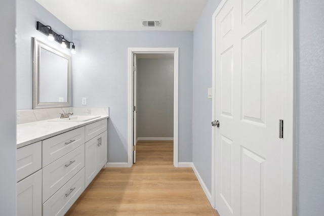 bathroom featuring baseboards, visible vents, wood finished floors, and vanity