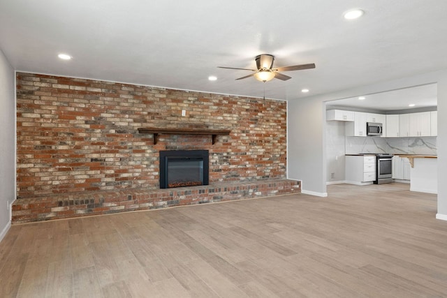 unfurnished living room with baseboards, a ceiling fan, light wood-style flooring, a brick fireplace, and recessed lighting