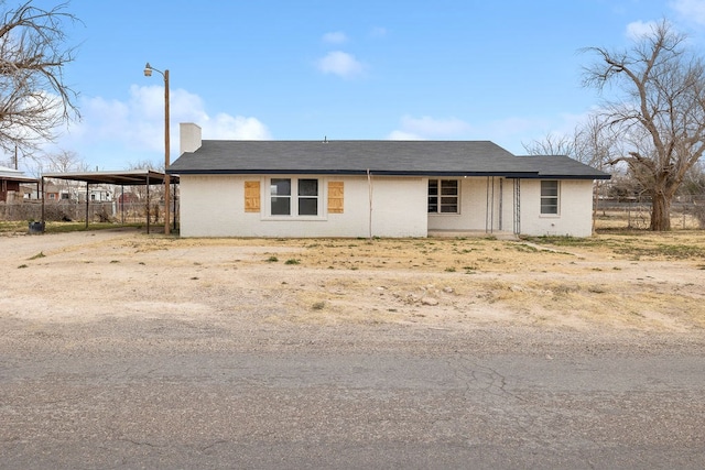 ranch-style home featuring an attached carport, fence, and dirt driveway