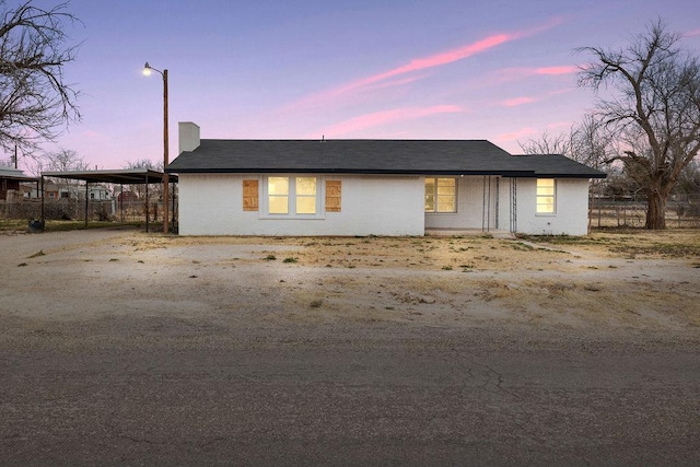 view of front of house featuring roof with shingles, driveway, and fence