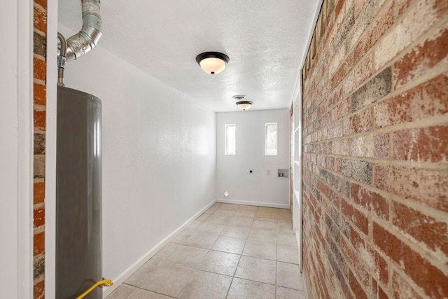 interior space with baseboards, a textured ceiling, brick wall, and light tile patterned floors