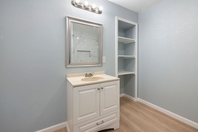 bathroom featuring wood finished floors, vanity, and baseboards