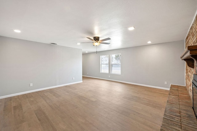 unfurnished living room with light wood-style floors, a fireplace, baseboards, and a ceiling fan