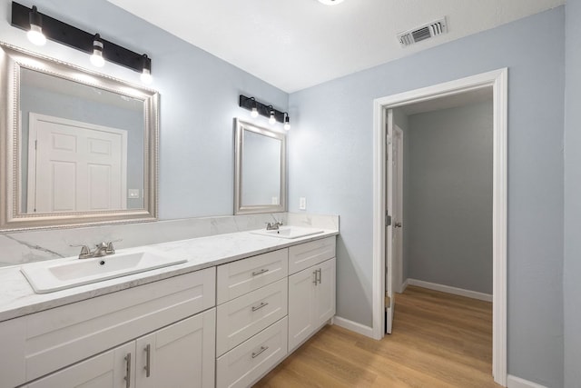 full bathroom featuring double vanity, wood finished floors, a sink, and visible vents