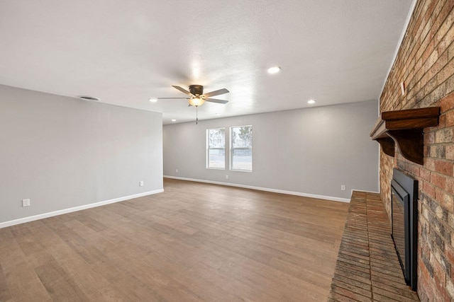 unfurnished living room with baseboards, a fireplace, visible vents, and wood finished floors