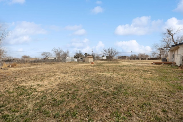 view of yard with a shed, fence, cooling unit, and a rural view