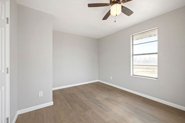 empty room featuring ceiling fan, baseboards, and wood finished floors